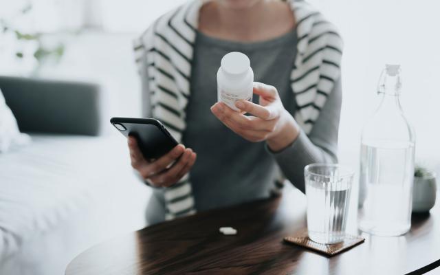 Woman on phone holding pill bottle